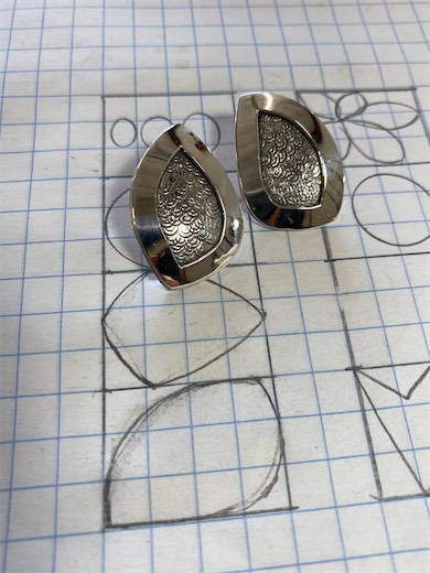 Two patterned gemstone earrings on gridded paper