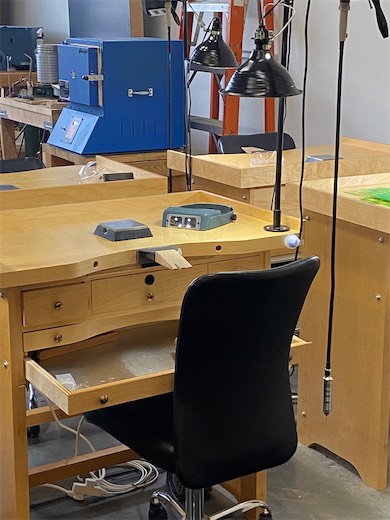 Jewelry-making bench with tools and a chair