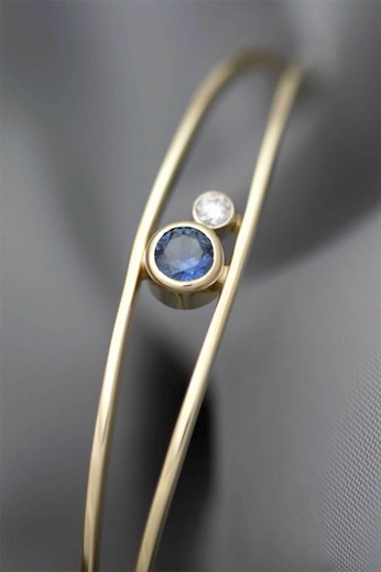 Open bracelet with blue and clear gemstone accents